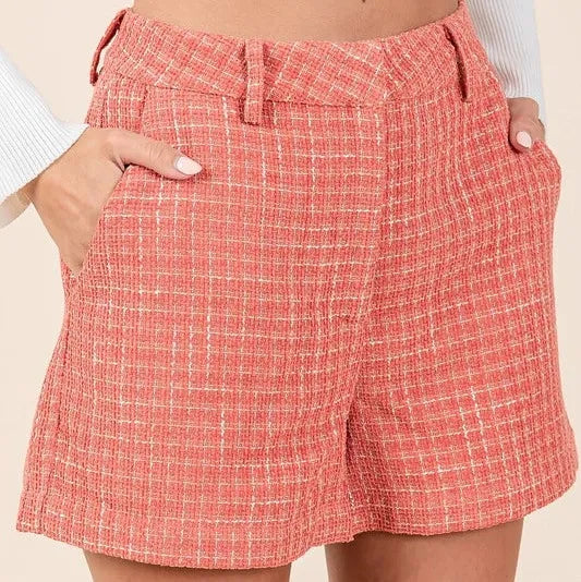 Red plaid shorts worn by a person on a beige background